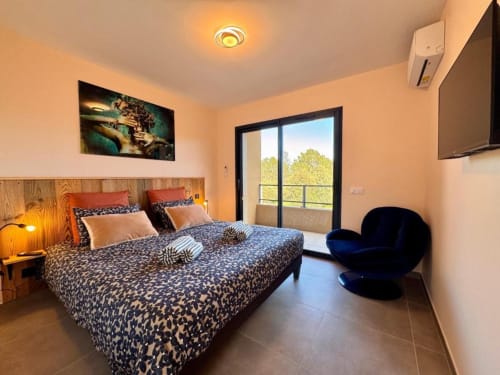 Chambre moderne de la Villa Dolce Vita à Porto-Vecchio avec parure léopard, vue sur balcon et décoration contemporaine