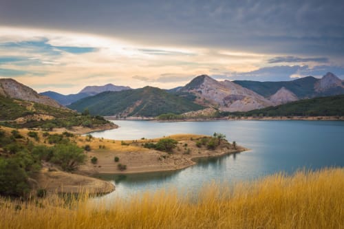 Lago de montaña pintoresco con colinas verdes y prados dorados en Casona del Porma, España