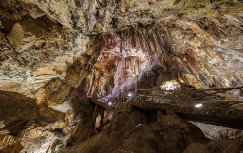 Interior dramático de cueva con estalactitas colgantes y pasarelas en Casona del Porma, España