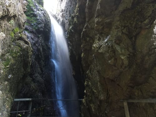 Estrecha garganta con cascada y paredes rocosas cubiertas de musgo en Casona del Porma, España