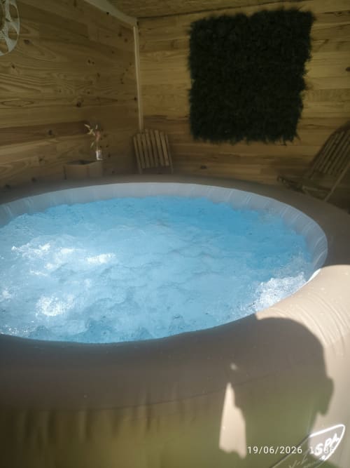 Bain à remous en cabane bois aux Insolites de la Bastide, eau bleue bouillonnante et intérieur rustique