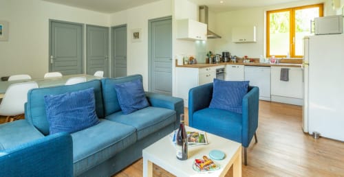 Modern open-plan living space at Clubhouse Gîtes in Beussent with blue sofa, kitchen, and dining area