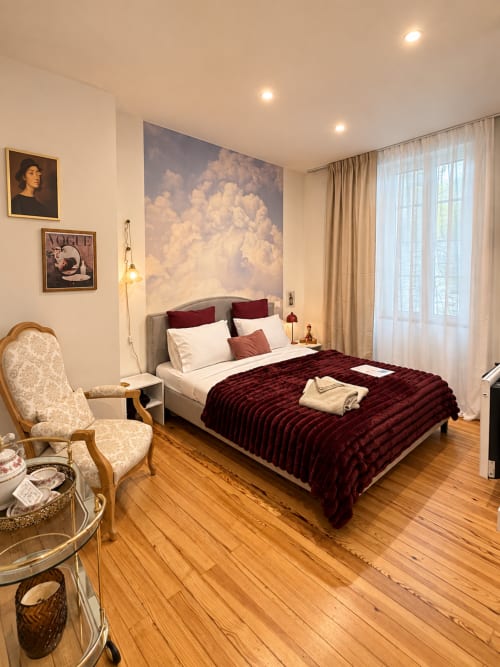 Chambre vintage à la Maison Farol B&B à Salles avec literie en velours bordeaux, art mural nuageux et parquet