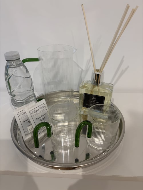 Aménités de la Suite Maison Farol : bouteille d'eau, pichet en verre, diffuseur de parfum avec tiges et verres sur plateau