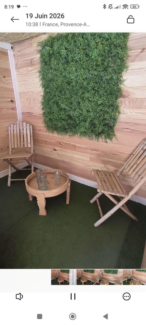 Intérieur de sauna en bois avec mur de mousse verte, chaises en bois et table ronde aux Insolites de la Bastide, France
