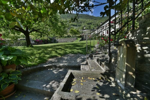 Giardino tranquillo a Roseto del Drago con laghetto in pietra, prato rigoglioso, panorama montano e pergolato ricoperto d'edera a Ponte in
