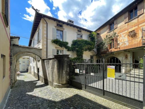 Ingresso del cortile medievale della Roseto del Drago B&B a Ponte in Valtellina con arco in pietra storico e edera rampicante