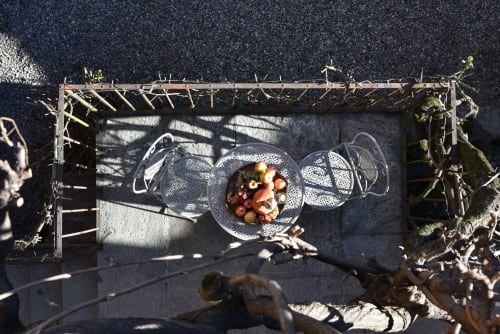 Vista dall'alto del balcone in pietra del piano nobile al Roseto del Drago con tavolino in ferro battuto e vassoio di frutta autunnale a Ponte in Valtellina.