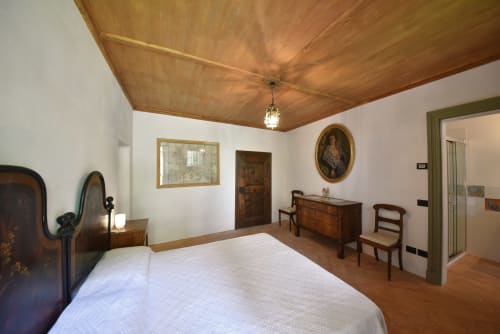 Camera spaziosa con soffitto in legno, pareti bianche, arredamento antico e pavimenti in legno presso Roseto del Drago B&B