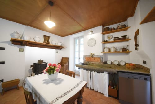 Rustico appartamento con cucina a Roseto del Drago, ripiani in legno, tavolo da pranzo con fiori rosa e vista sul giardino