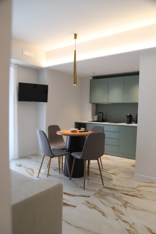 Moderna zona cucina-living a Totonno's Rooms, Tropea con pavimento in marmo, mobili verdi e sedute contemporanee