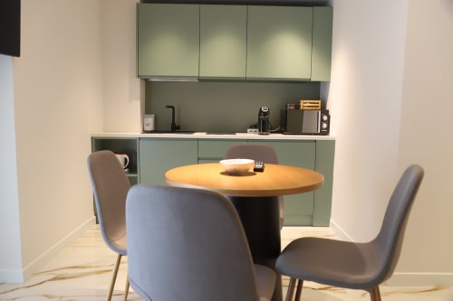 Angolo cucina moderno a Totonno's Rooms a Tropea con tavolo rotondo in legno, sedie grigie e mobili verde salvia