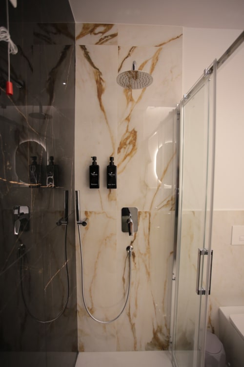 Moderno bagno nella villetta i Lianu di Totonno's Rooms a Tropea, con pareti effetto marmo e soffione pioggia