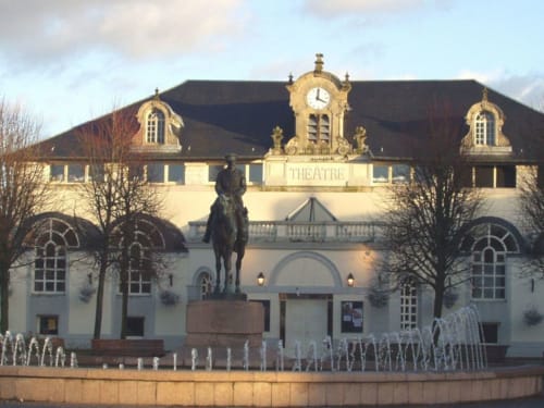 Bâtiment de théâtre historique avec tour horloge à Beussent, France, orné d'une statue équestre et d'une fontaine