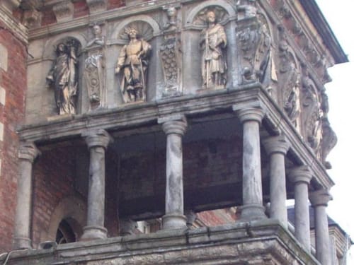 Façade en pierre historique de la Maison d'Hôtes Clubhouse Gîtes à Beussent, France, avec colonnes ornées et reliefs sculptés