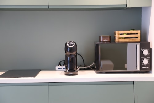 Angolo cucina a Totonno's Rooms Tropea con macchina per caffè, microonde e organizer in legno