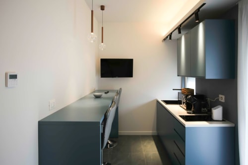Cucina moderna nelle camere Totonno's di Tropea con mobili scuri, lampade a sospensione e TV a parete