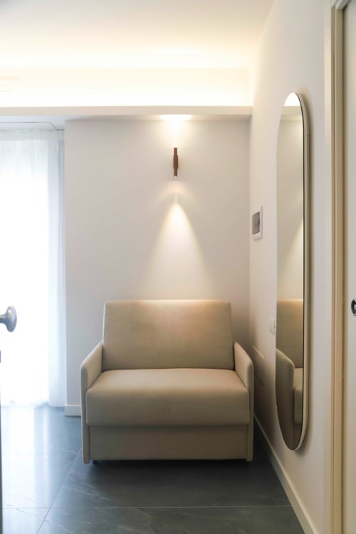 Moderna nicchia con poltrona beige e specchio rotondo nella suite di Totonno's Rooms a Tropea