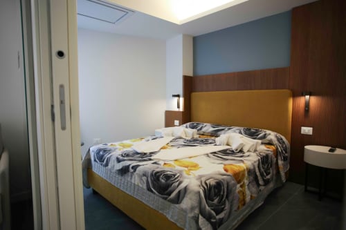 Camera moderna alle Totonno's Rooms di Tropea con testata dorata, biancheria a motivi e parete blu-marrone