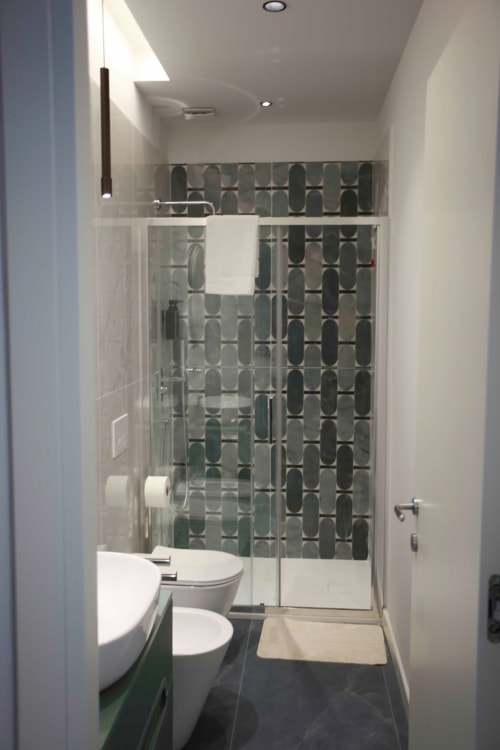 Bagno moderno alle Camere Totonno a Tropea con doccia a piastrelle decorate, WC e lavabo bianco