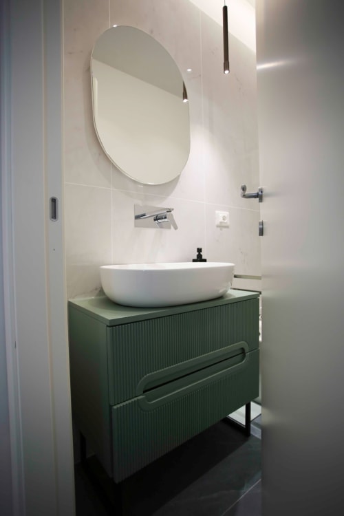 Bagno moderno a Totonno's Rooms Tropea con specchio ovale, lavabo bianco e mobile verde