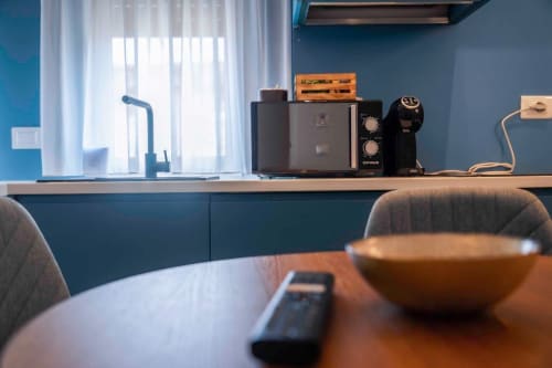 Cucinetta moderna nelle Rooms Tropea con pareti blu, macchina per espresso e vista sulla città