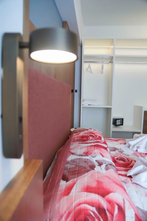 Camera moderna alle Totonno's Rooms Tropea con letto in rosso, lampada da parete e cabina armadio integrata