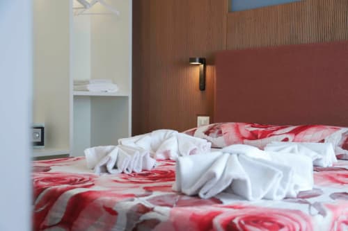 Camera moderna alle Totonno's Rooms a Tropea con biancheria rossa floreale e decorazioni di asciugamani bianchi, vista sulla città