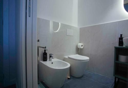Moderno bagno nell'appartamento Totonno's Rooms a Tropea con bidet, wc, lavabo e pavimentazione in piastrelle grigie