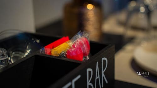 Minibar nelle Moon Rooms By Celeste, lussuosa struttura ricettiva a Catania con bottiglie rosse e gialle esposte su ripiano nero