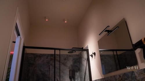Bagno moderno con doccia in cristallo, illuminazione d'atmosfera e finiture in marmo presso Moon Rooms Catania