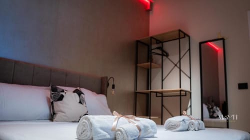 Camera Deluxe King presso Moon Rooms By Celeste a Catania con asciugamani arrotolati, illuminazione al neon, arredamento moderno e viste sui monumenti della città