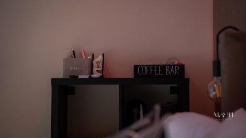 Angolo caffè nella Junior Suite Moon Rooms di Catania con porta utensili e insegna al neon su scaffale nero