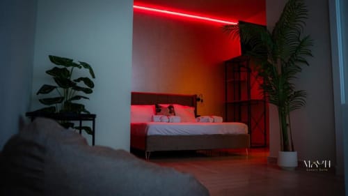 Deluxe King Room presso Moon Rooms By Celeste a Catania con luci neon rosse, letto moderno, piante in vaso e vista sulla città