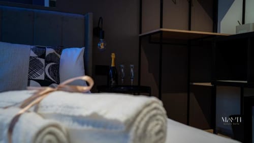 Camera Deluxe con Letto Queen presso Moon Rooms By Celeste a Catania con asciugamani arrotolati, bottiglia di champagne e arredi moderni scuri