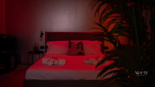 Camera Deluxe King moderna presso Moon Rooms By Celeste a Catania con illuminazione ambientale rossa, piante decorative e vista sulla città