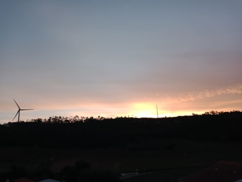 Vista do pôr do sol da villa Feather House em São Bartolomeu com aerogeradores silhuetados contra o céu dourado