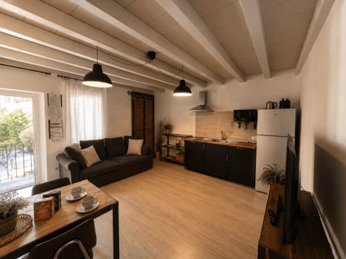 Monolocale moderno a Bergamo con spazio living aperto, angolo cottura, divano scuro, tavolo in legno e illuminazione contemporanea