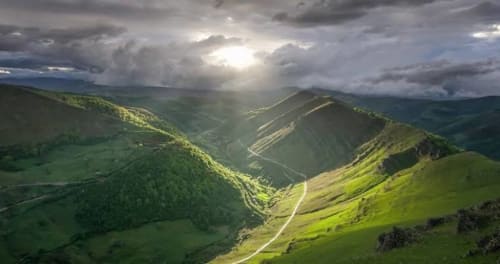 Exuberante valle montañoso verde cerca del hotel La Calleja Real en Liérganes, España con carreteras sinuosas y cielo nublado dramático
