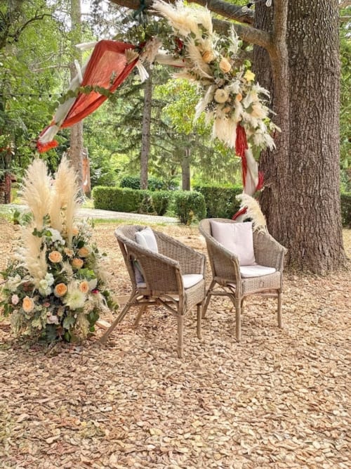 Cérémonie de mariage en plein air à Les Loyes B&B à Jaillans avec arche décorée, fleurs et sièges en osier