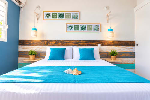Chambre Quetzal Aigue-marine avec accents turquoise, tête de lit en bois et vue sur la piscine à Sainte-Anne, Guadeloupe