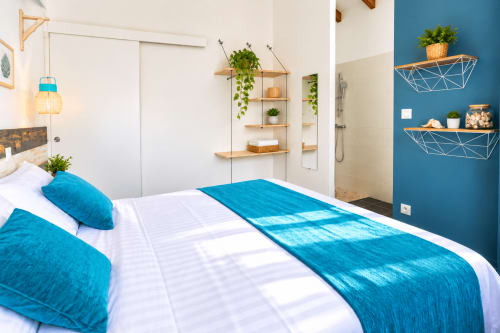 Chambre bleu-vert au Quetzal à Sainte-Anne avec accents turquoise, étagères en bois et vue sur la piscine