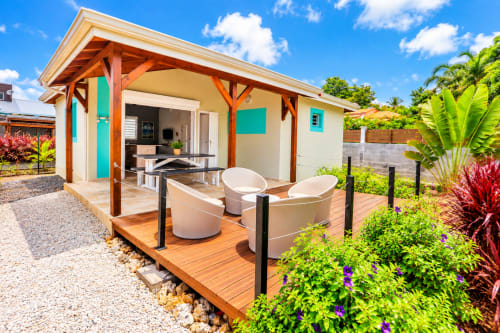 Appartement Aigue-marine au Quetzal à Sainte-Anne avec terrasse en bois, chaises longues, jardin tropical et terrasse moderne
