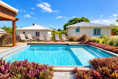Vue de la piscine de l'appartement Aigue-marine du Quetzal BnB à Sainte-Anne avec chaises longues et paysage tropical