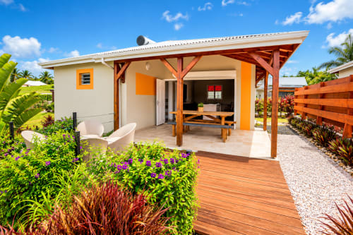 Bungalow tropical moderne au Quetzal, Sainte-Anne avec accents orange, terrasse bois et jardins luxuriants