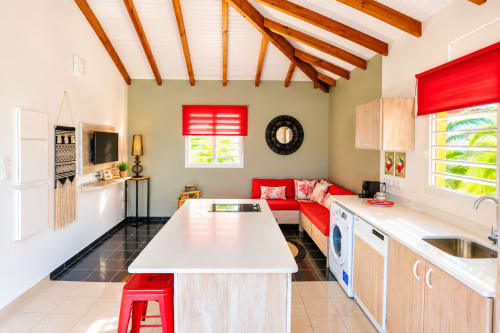 Cuisine moderne et séjour de l'appartement Kâz corail au Quetzal BnB, Sainte-Anne, Guadeloupe avec touches rouges