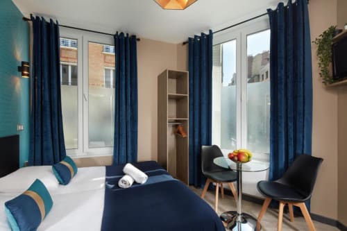 Modern studio twin bedroom at Résidence Aurmat boutique hotel, Paris with navy curtains and contemporary furnishings