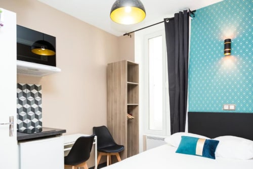 Chambre studio double moderne à la Résidence Aurmat Paris Boulogne avec mur d'accent turquoise, bureau, kitchenette et