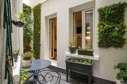Lush green vertical gardens frame a modern patio at Résidence Aurmat Paris, featuring dining table and potted plants