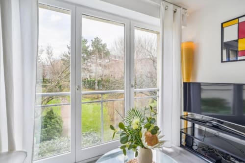 Modern 1-bedroom apartment with garden views at Résidence Aurmat Paris Boulogne, featuring floor-to-ceiling windows, living